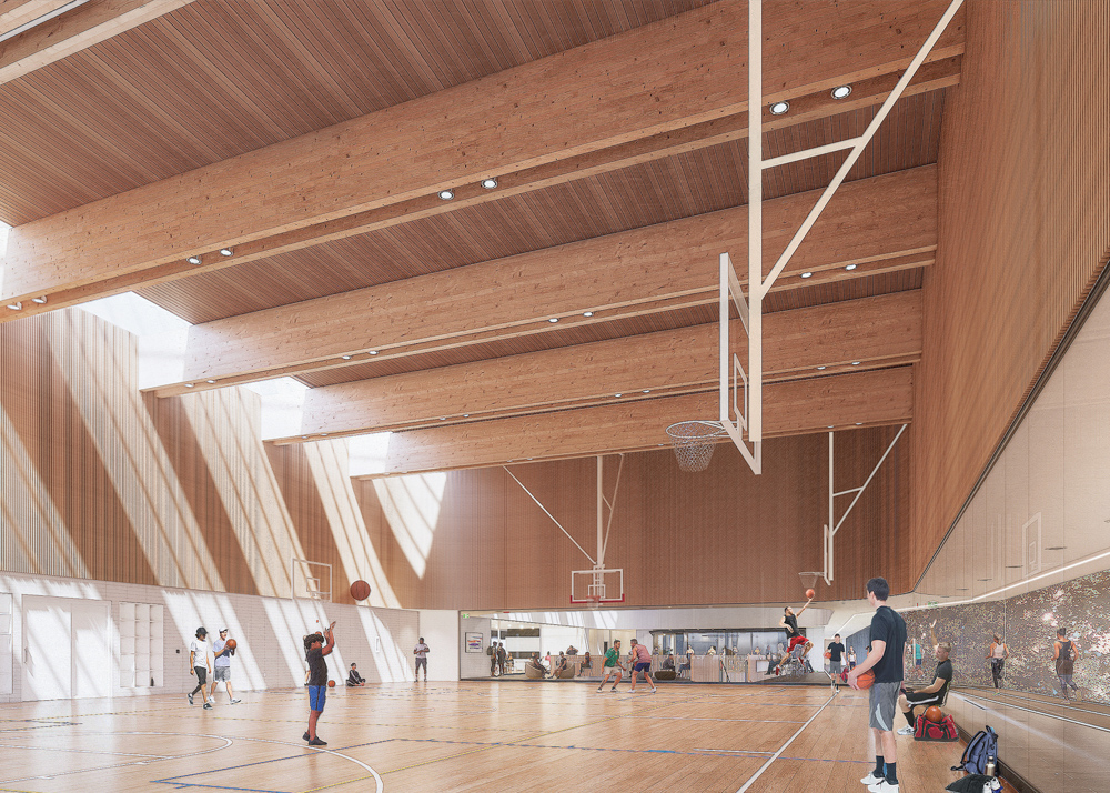 Rendering of the gymnasium in the community centre, which has a high wooden ceiling, wooden beams and skylights on one side. Multiple basketball nets are suspended from the ceiling above a wooden court with line markings. The wall on the left side is tiled and features cubbies. A transparent wall curves around the other sides of the space, providing views into the adjacent lounge and running track on the right.