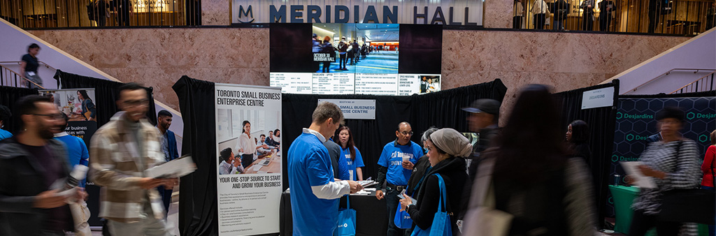 People milling about in the lobby of a trade show at Meridian Hall in Toronto.