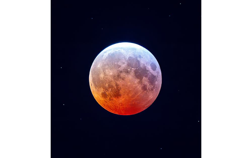 A partially eclipsed moon glows with orange and white hues against a dark, starry sky.