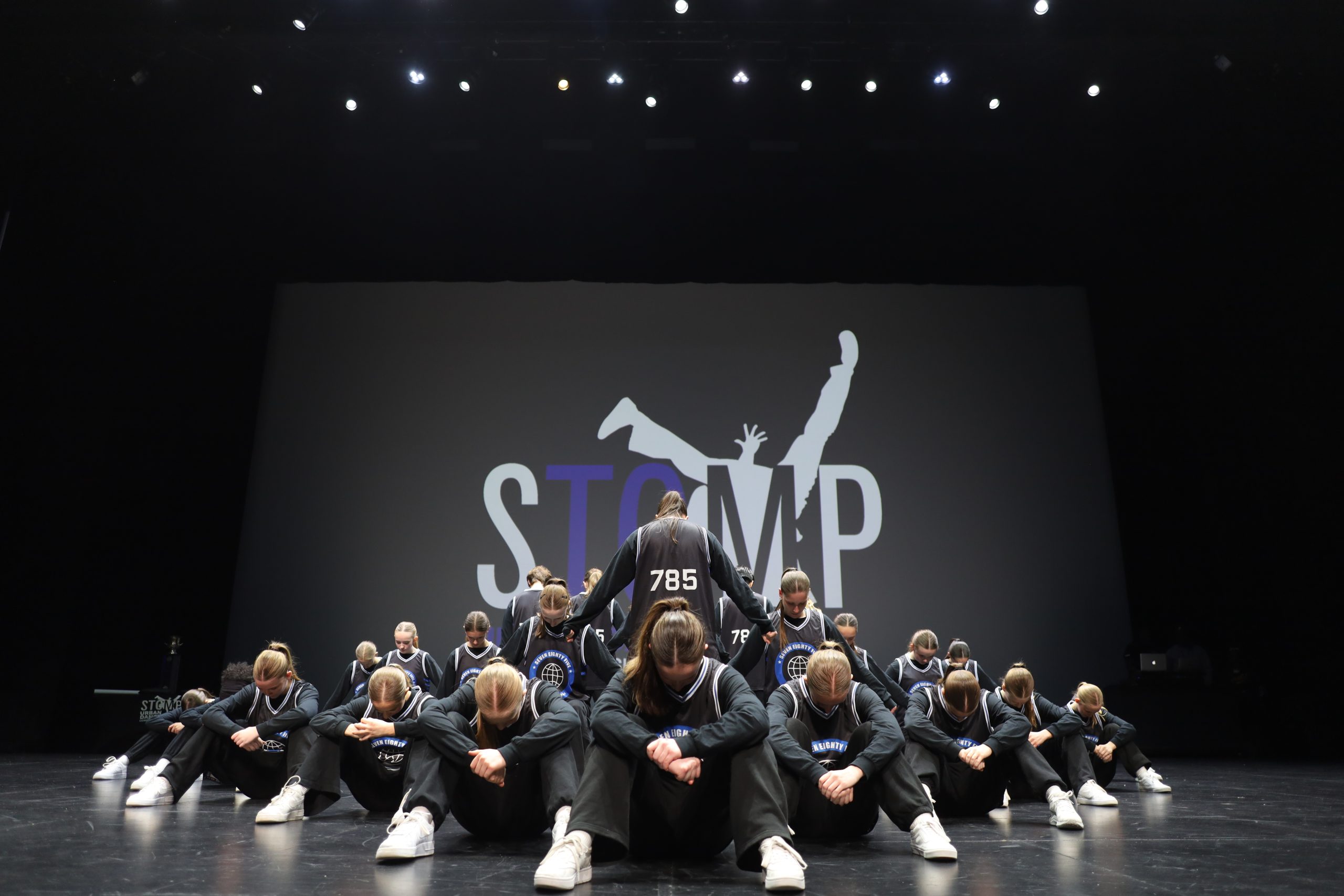 Dancers in black outfits perform on stage with a 