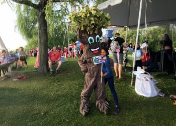 A person dressed as a tree posing with a child holding a sign that reads Live Green Toronto.