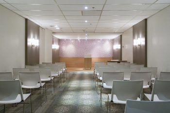 A view of the North York Civic Centre Wedding Chamber when standing at the back facing the podiumn. There are about 30 chairs shown in the image with an aisle in the centre.