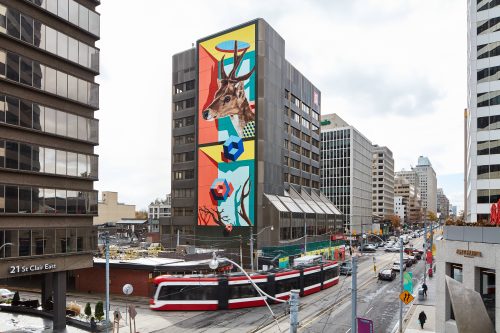 Toronto street artist birdO added colour and life to the urban landscape at Yonge and St. Clair with his newest 10-storey mural at 1 St. Clair E. A towering image of a deer is mixed with birdO’s signature surrealist style, playfully referencing the surrounding Deer Park neighbourhood.