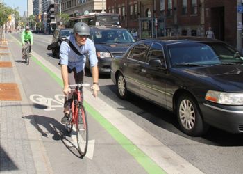 A cyclist in a bike lane as cars pass by.