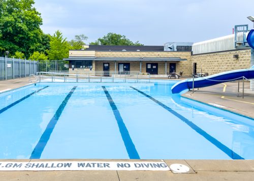 Vacant outdoor pool with marked lanes and water slide.