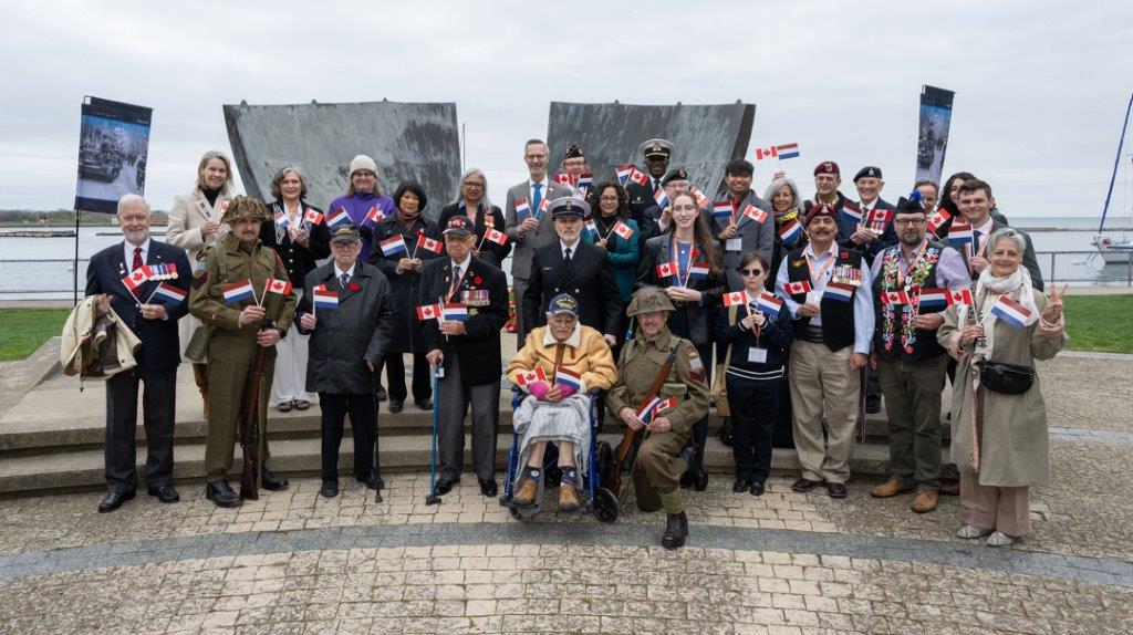 Group standing in front of a monument, all holding paper flags