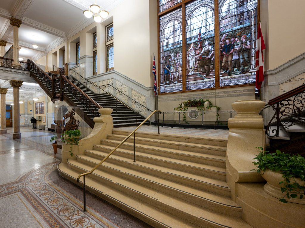 Stairs leading to second floor with stained glass window in background
