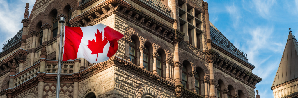 Facade of old city hall with a Canadian flag in the foreground