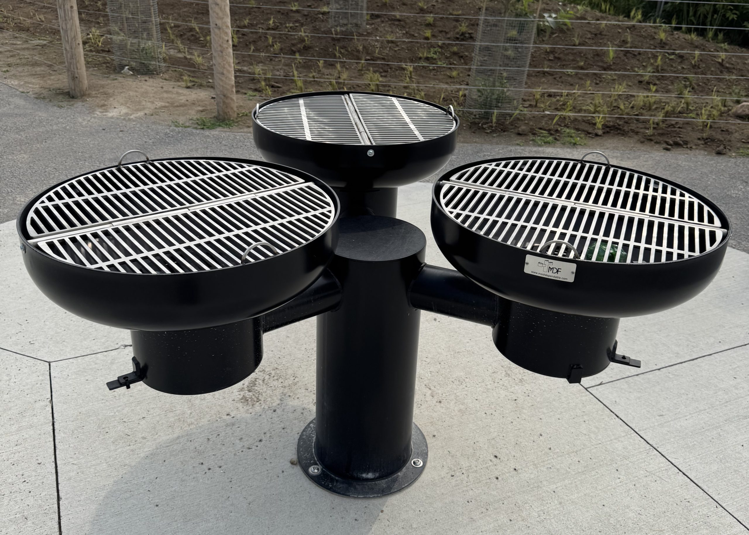 Three grills/barbeques arranged around one singular pillar.