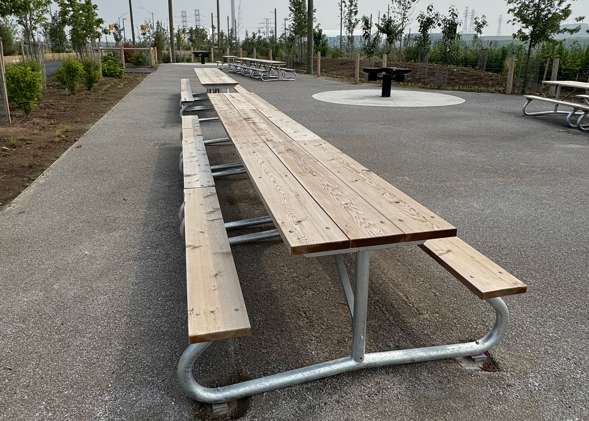 Long picnic tables in rows with a BBQ in the background.