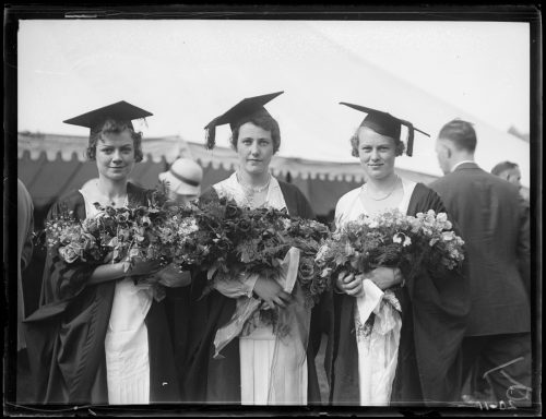 Three female University of Toronto graduates holding bouquets of flowers
