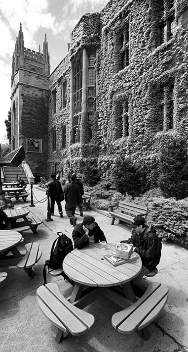 Two students sit at a picnic table outside the Hart House at University of Toronto.