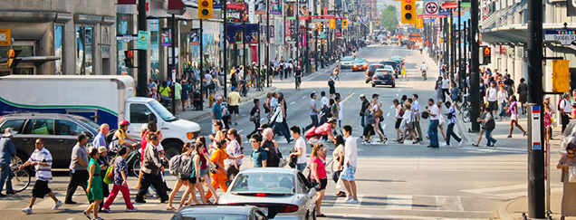 View north up Yonge Street from Dundas Street, showing a busy intersection with many pedestrians, vehicles, and storefronts lined with signs and banners.