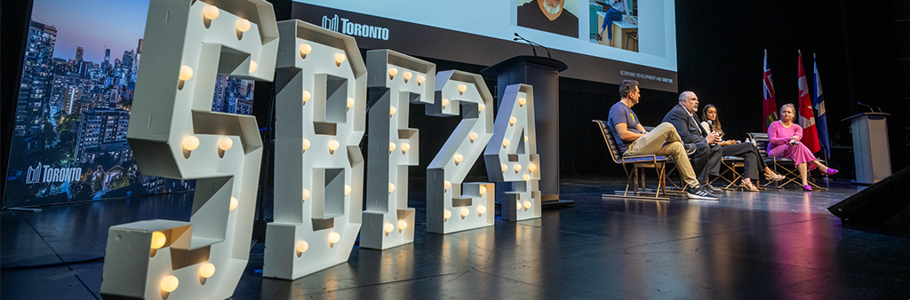 Panel of four people on stage with marquee lights SBF 24