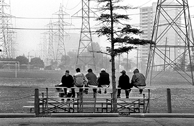 A group of teens sit on bleachers overlooking a soccer field in a hydro corridor.