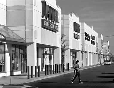 A person walks across the parking lot at a large retail plaza.