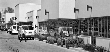 A man walks towards single storey office buildings.