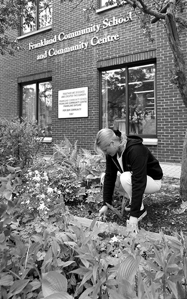 - A woman gardens outside Frankland Community School and Community Centre.
