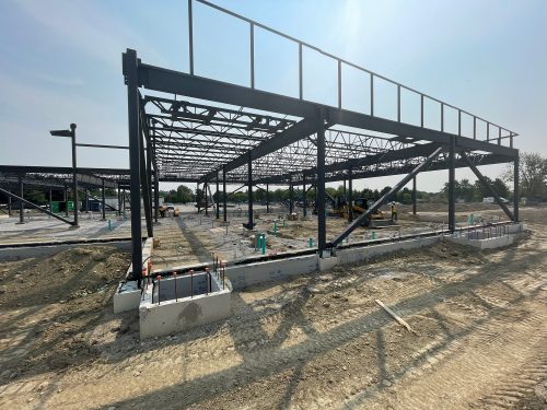 The fieldhouse at the new soccer hub under construction, showing the completed steel structure. The rectangular one-storey structure rests on a concrete foundation.
