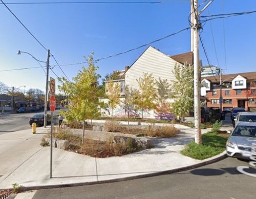 Photo of a public plaza with trees and other plantings, seating and permeable elements.