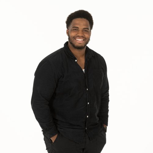 A man dressed in all black standing Infront of a white backdrop