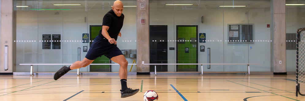 Man playing indoor soccer, preparing to kick the ball.