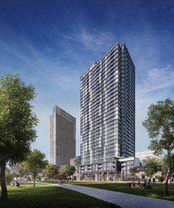 A tall building with many windows, blue skies, and someone riding on a bike on the sidewalk. 