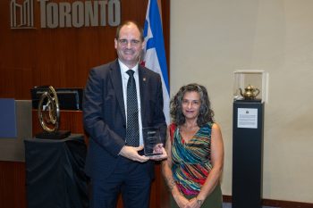 Two people pose for a photo with an award.