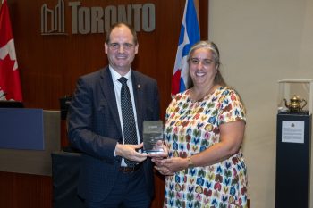Two people pose for a photo with an award.