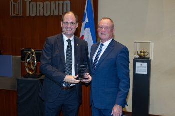 Two people pose for a photo with an award.
