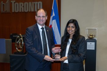 Two people pose for a photo with an award.