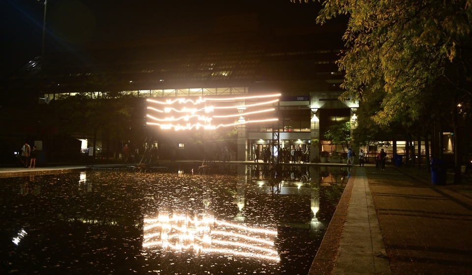 Lines of neon lights over a pool of water at night