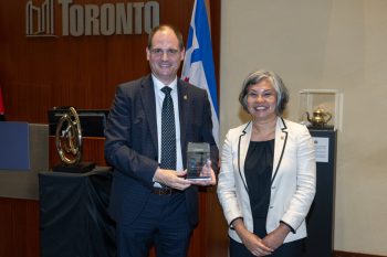 Two people pose for a photo with an award.