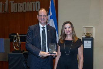 Two people pose for a photo with an award.