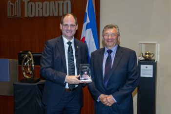 Two people pose for a photo with an award.