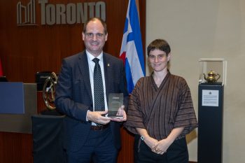 Two people pose for a photo with an award.