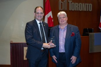 Two people pose for a photo with an award.