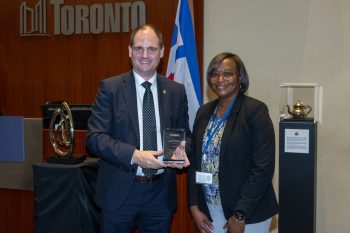 Two people pose for a photo with an award.