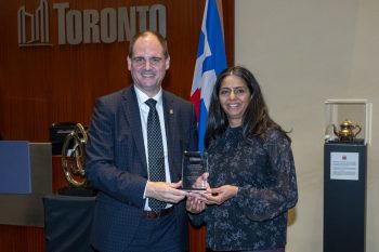Two people pose for a photo with an award.