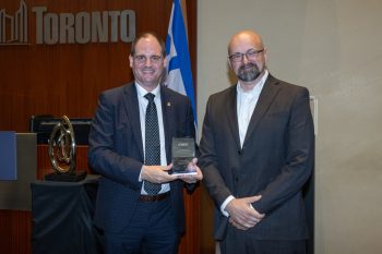 Two people pose for a photo with an award.
