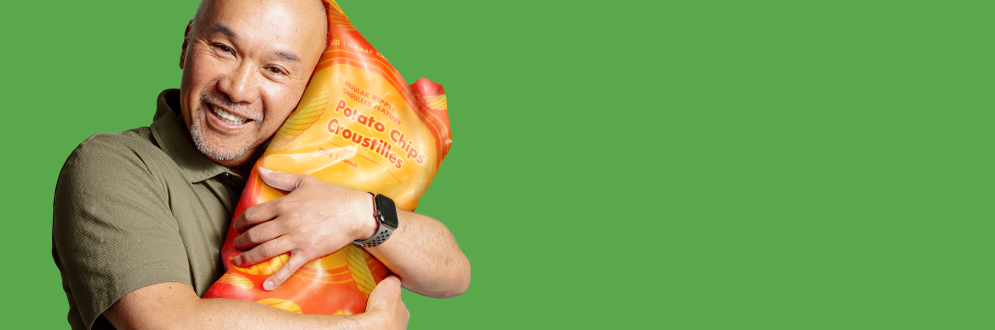 A man smiling and holding a bag of potato chips