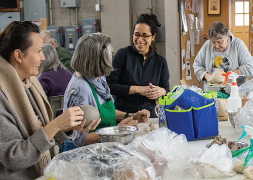 People sitting around a large workspace on making art projects.