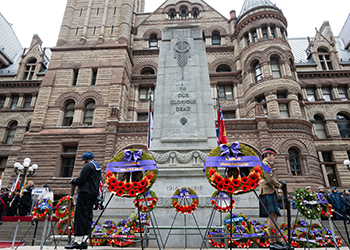 The Toronto Cenotaph at Old City Hall during a Remembrance Day ceremony adorned with commemorative wreaths.