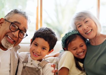 Grandparents sitting on the couch with their grandchildren smiling.