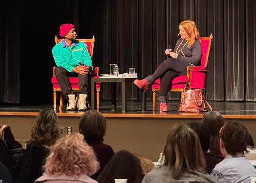 Two seated people in conversation on a stage in front of an audience