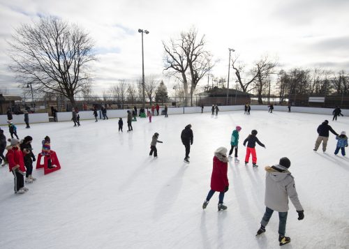 People public skating on an outdoor skating rink during the day time.