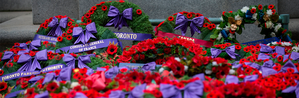 Many Remembrance Day wreaths covered with poppied and purple ribbons.