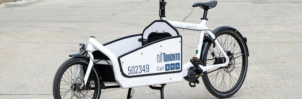Image of a white cargo e-bike with the City of Toronto logo on it.