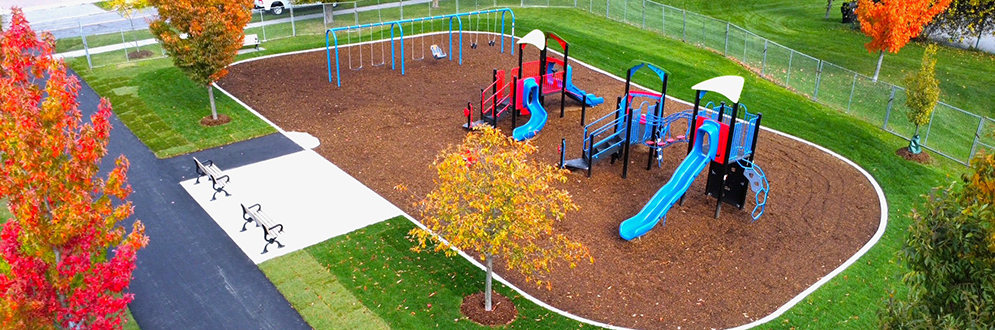 Birdseye view of the new playground at Grandravine Park after construction, featuring a swing set and two main play structures with slides and climbing elements.