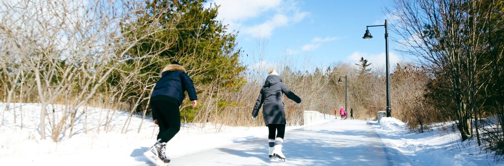 Ice Skaters along the ice skate path at Colonel Samuel Smith Park on a clear winter day.